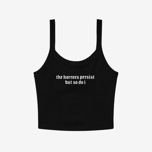 May include: Black tank top with thin straps. The white text on the front reads "the horrors persist but so do i". The top is a solid color and has a scoop neckline.