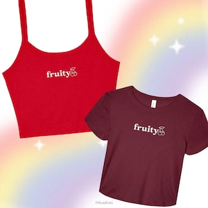 May include: Two crop tops, one red and one maroon, with the word "fruity" and a cherry graphic. The red top has spaghetti straps, while the maroon top is a t-shirt. The background has a rainbow gradient.