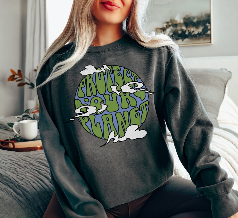 May include: A dark grey sweatshirt with a green and blue graphic of the Earth with the text "Protect Our Planet" in a retro font.