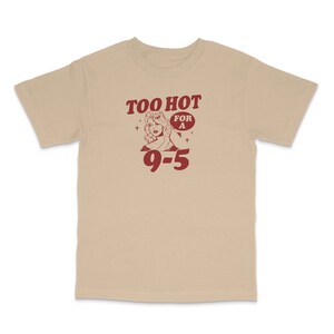 May include: Beige t-shirt with a red graphic of a woman with the text "Too Hot For A 9-5".
