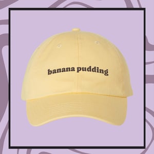May include: A yellow baseball cap with the text "banana pudding" embroidered in brown on the front.