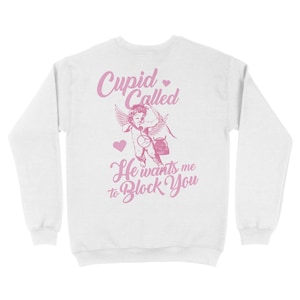 May include: White sweatshirt with a pink graphic of Cupid with an arrow and the text "Cupid Called He wants me to Block You".
