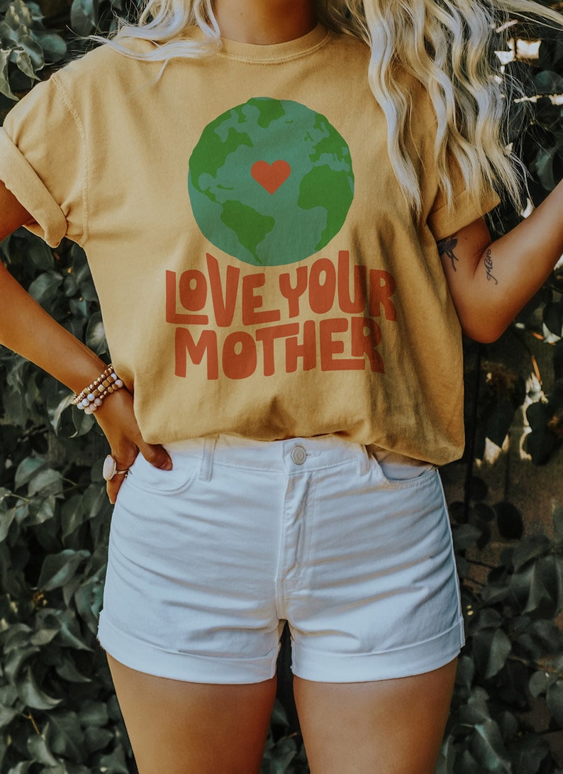May include: A yellow t-shirt with a green and blue globe graphic and the text "LOVE YOUR MOTHER" in red and orange letters.