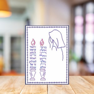 May include: A white cross-stitch design with a blue border. The design features two candles with flames and a woman in a white head covering. The Hebrew text on the design reads "Kadosh Kadosh Kadosh" and "Adonai Tsevaot Maleh Kol Haaretz Kavodoh".