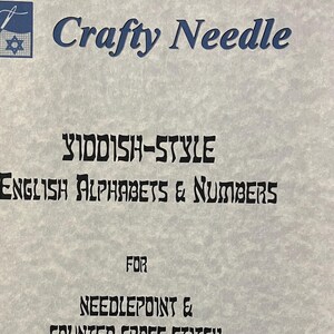 May include: A light gray paper with the text "Crafty Needle" in blue. The text "Yiddish-Style English Alphabets & Numbers" is in black. It is for needlepoint and counted cross stitch. Contact information is at the bottom.