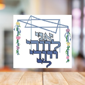 May include: A blue and white cross stitch pattern of a sukkah, a traditional Jewish shelter, with the Hebrew words "L'chaim" meaning "to life" written inside. The sukkah is decorated with flowers and vines.