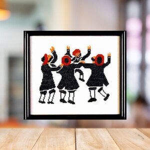 May include: A framed cross-stitch embroidery depicting five people in black clothing and red hats dancing in a circle. The background is white.