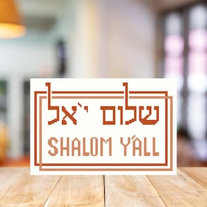 May include: A white sign with a brown border and the text "Shalom Y'all" in Hebrew and English.
