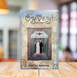 May include: A colorful quilt pattern featuring a wedding ceremony under a chuppah with the Hebrew text "Ayin K'li Yiddu Li" and the words "Mazel Tov Newlyweds".