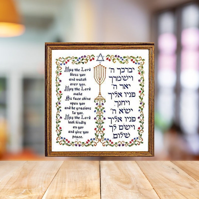 May include: A framed cross-stitch embroidery with a Hebrew blessing in a gold frame. The blessing reads "May the Lord bless you and watch over you. May the Lord make His face shine upon you and be gracious to you. May the Lord look kindly on you and give you peace." The Hebrew text is in blue and red, and the English text is in black.