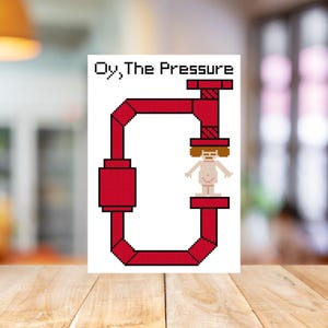 May include: A white card with the text "Oy, The Pressure" above a red pipe design. The design includes a stick figure inside the pipe. The card is on a wooden surface.