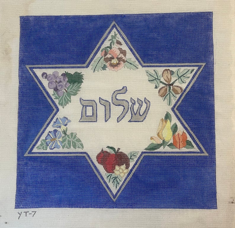 K&ouml;nnte beinhalten: Eine wei&szlig;e Leinwand mit blauem Hintergrund, auf der ein gro&szlig;er sechszackiger Stern mit dem hebr&auml;ischen Wort "Shalom" in der Mitte abgebildet ist. Der Stern ist von verschiedenen floralen und fruchtigen Motiven umgeben.