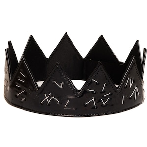 May include: A black crown with a pointed design and white stitching. The crown is made of a shiny material.