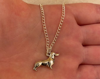 May include: Silver chain necklace with a silver dachshund pendant.