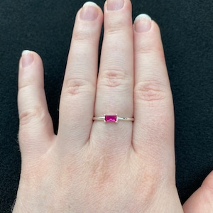 May include: A silver ring with a pink rectangular gemstone.