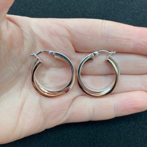 以下が含まれることがあります： 2色のデザインのフープイヤリングのペア。外側のフープはシルバーで、内側のフープはローズゴールドです。