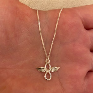 May include: Silver necklace with an infinity symbol pendant with angel wings.