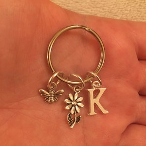 May include: Silver key chain with a bee, flower, and letter K charm.