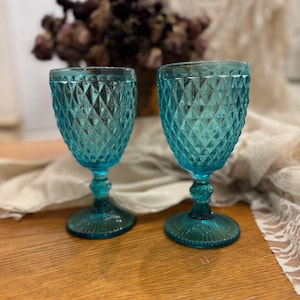 May include: A set of three ceramic mugs with a speckled, cream-colored glaze. Each mug features a different hand-painted floral design in shades of blue, green, and yellow. The mugs have a simple, modern shape.