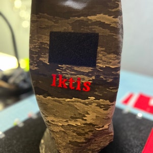 May include: A camouflage-patterned fabric pouch with a black velcro patch and the word "Iktis" embroidered in red.