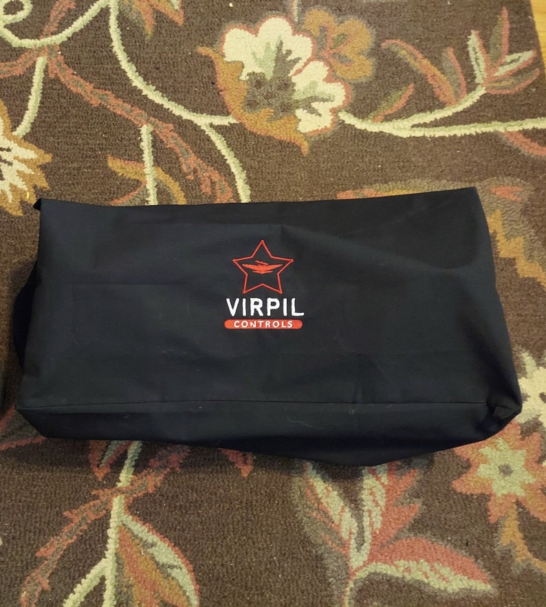 Puede incluir: Funda de transporte negra con una estrella roja y el texto "VIRPIL CONTROLS" bordado en la parte delantera.