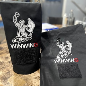 Puede incluir: Dos bolsas de tela negra con un diseño bordado en blanco de una figura sosteniendo una antorcha. Las bolsas tienen el texto "Orion Winwing" bordado. Cada bolsa tiene un parche de velcro negro.