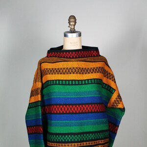 May include: A colorful striped sweater with a high neck and long sleeves. The sweater is made of a thick, woven fabric and features a variety of colors, including red, orange, yellow, green, blue, and black.