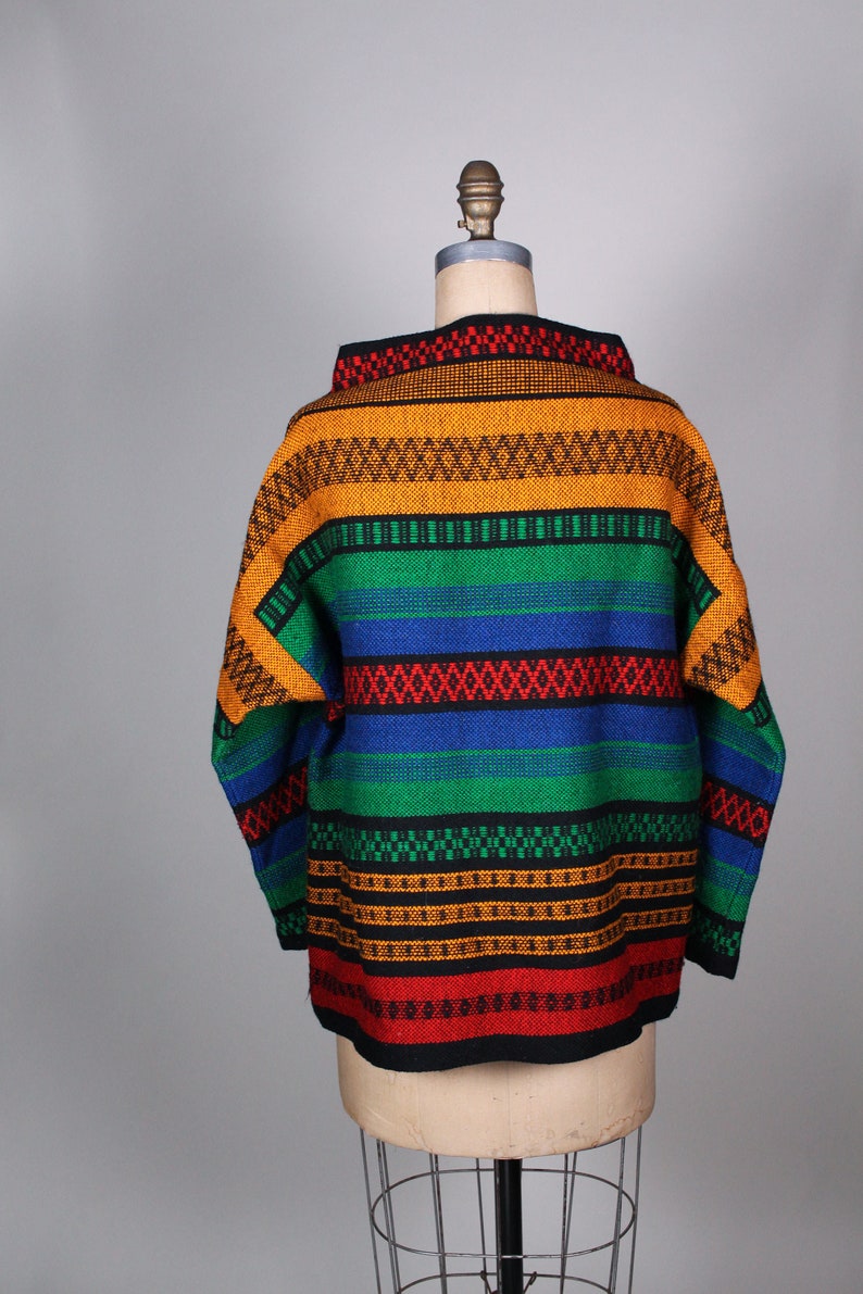 May include: A colorful striped sweater with a high neck and long sleeves. The sweater is made of a thick, textured fabric and features a variety of colors, including red, orange, yellow, green, blue, and black.