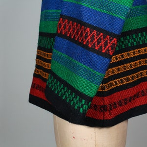 May include: A colorful striped fabric with black, red, green, blue, and orange stripes. The fabric is woven with a variety of patterns and textures.