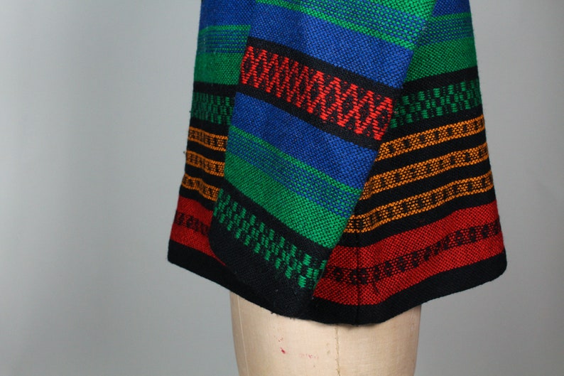May include: A colorful striped fabric with black, red, green, blue, and orange stripes. The fabric is woven with a variety of patterns and textures.