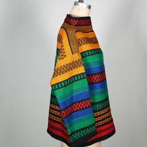 May include: A colorful striped sweater with a high neck and long sleeves. The sweater is made of a thick, textured yarn and features a variety of colors, including red, orange, yellow, green, blue, and black.