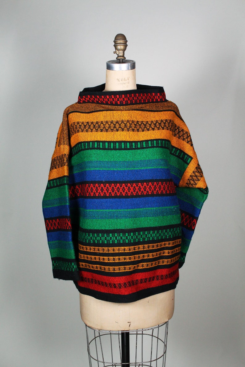 May include: A colorful striped sweater with a high neck and long sleeves. The sweater is made of a thick, woven fabric and features a variety of colors, including red, orange, yellow, green, blue, and black.