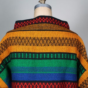 May include: A colorful woven sweater with a geometric pattern in shades of orange, green, blue, red, and black.