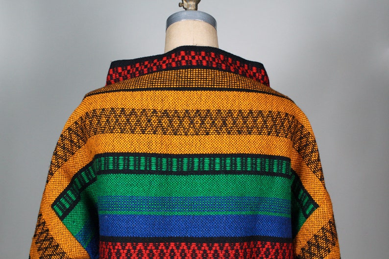 May include: A colorful woven sweater with a geometric pattern in shades of orange, green, blue, red, and black.