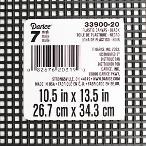 May include: Black plastic canvas with a grid pattern. The label indicates the canvas is 10.5 inches by 13.5 inches. The label also includes the text "Darice" and "Plastic Canvas - Black".