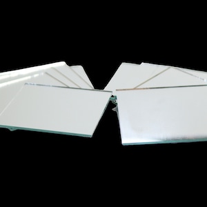 May include: A set of ten small, square, silver-backed mirrors. The mirrors are arranged in two stacks of five.