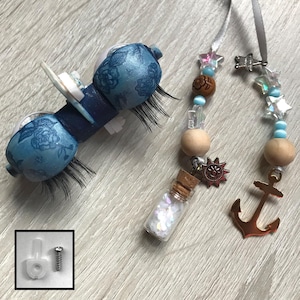 May include: A blue and white decorative car air vent clip with a floral design, and a set of beaded charms. The charms include wooden beads, star-shaped beads, a small bottle with glitter, and a copper anchor charm.