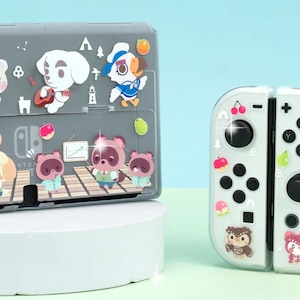 Pode incluir: Capa cinza para Nintendo Switch e Joy-Cons brancos decorados com personagens de desenhos animados e frutas. A capa do Switch apresenta vários personagens, enquanto os Joy-Cons têm designs de frutas e personagens. O fundo é azul claro.