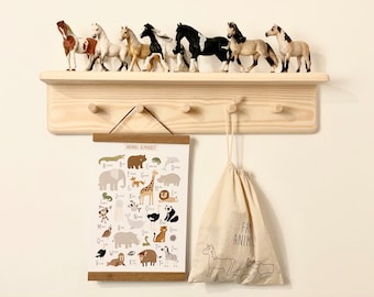 May include: A wooden shelf with five hooks, a canvas bag with the text "Farm Animals" hanging from one hook, and a framed animal alphabet poster hanging below the shelf. There are eight toy horses on the shelf.