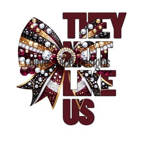 Può includere: Un fiocco da cheerleader rosso, oro e bianco con strass e un testo sovrapposto "THEY NOT LIKE US" in rosso, oro e bianco.