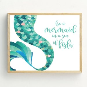 May include: A teal blue mermaid tail with pink scales and the text "be a mermaid in a sea of fish" on a white background.