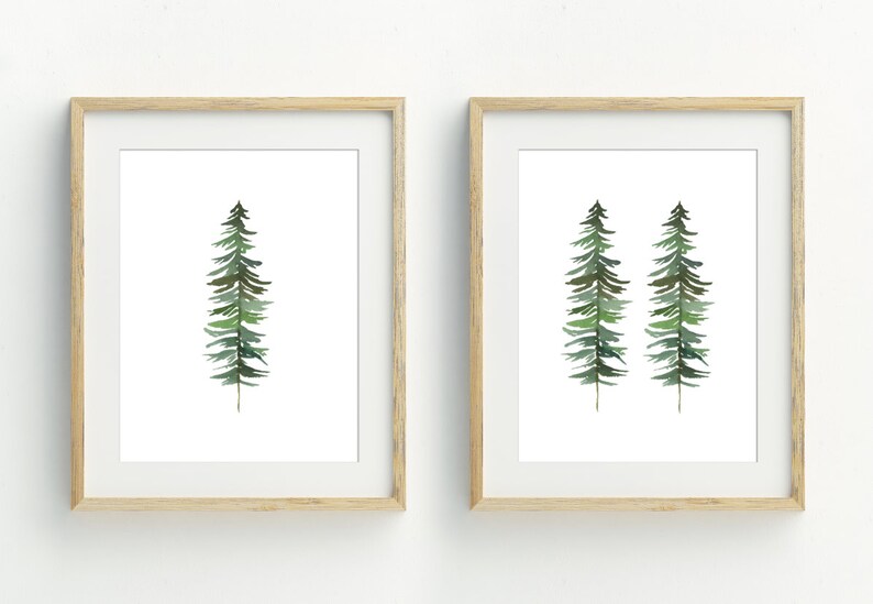 May include: Two framed watercolor paintings of stylized green pine trees. The first painting features a single tree, while the second painting features two trees.