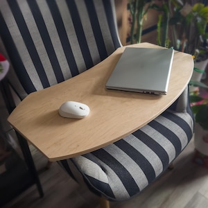 以下が含まれることがあります： 白のコンピューターマウスとシルバーのラップトップが置かれた、明るい色の木製ラップトップデスク。 デスクは、グレーとネイビーブルーの色合いのストライプ模様の椅子の上に置かれています。
