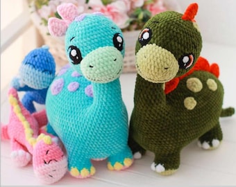 May include: A collection of handmade crochet dinosaur toys in various colors. The dinosaurs include a blue one with purple spots, a green one with red accents, a pink one with a yellow spine, and a blue one. Each toy has large, expressive eyes.