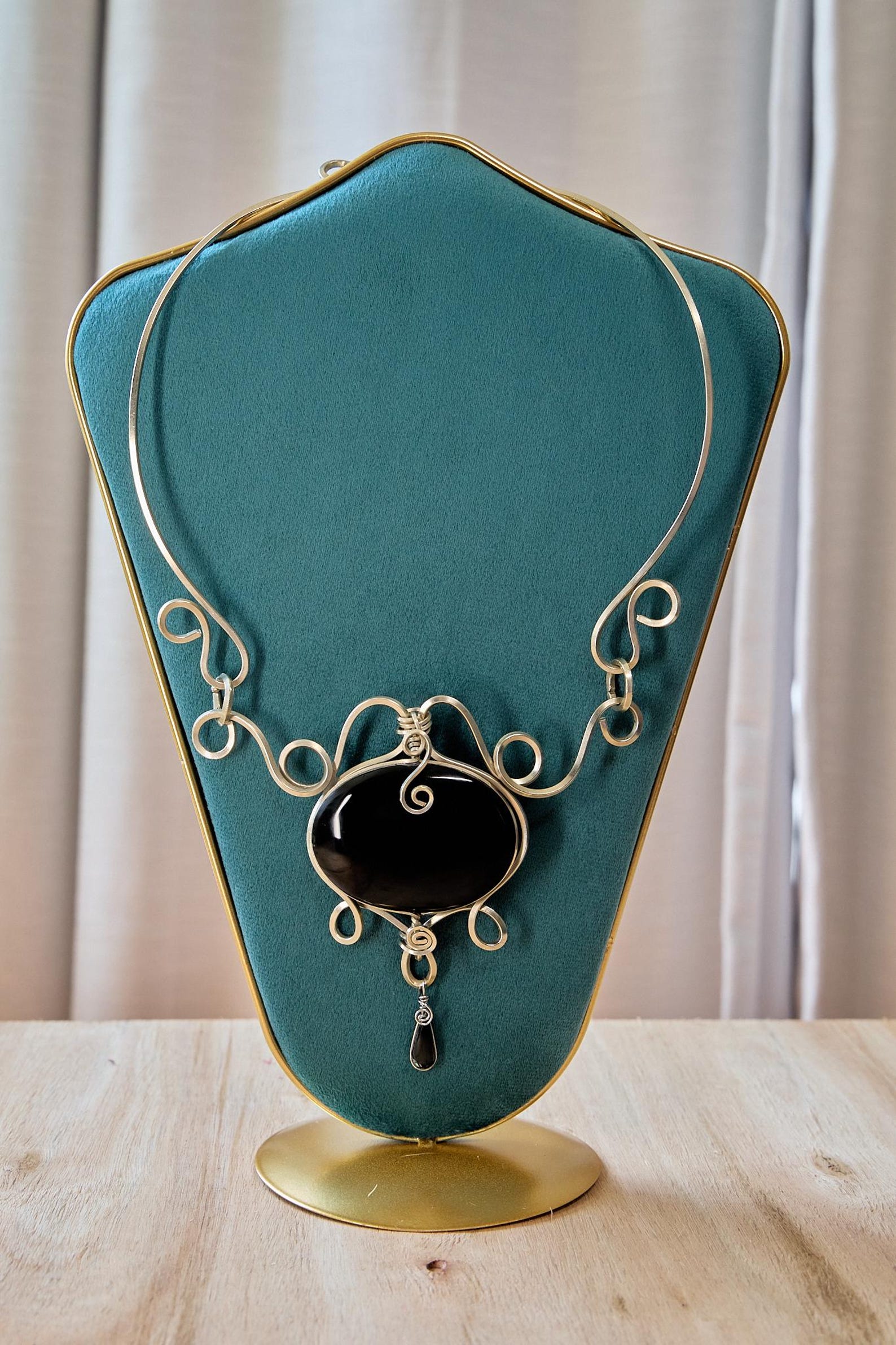 Handmade Mexican black obsidian statement necklace with ornate silver wire design on a display bust.