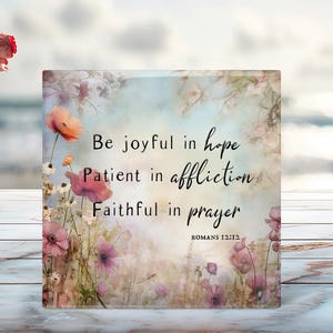 May include: A floral design with a quote about hope, patience, and prayer. The quote reads "Be joyful in hope, Patient in affliction, Faithful in prayer." The quote is attributed to Romans 12:12.