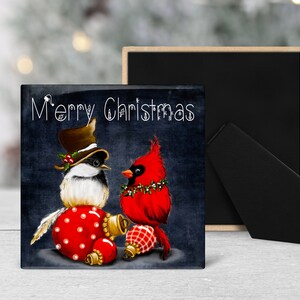 May include: Square Christmas-themed artwork featuring two stylized birds. One bird wears a top hat and sits atop a red, polka-dotted ornament. The other is a red cardinal. The words "Merry Christmas" are written across the top.
