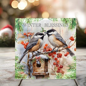 May include: A square glass coaster with a winter scene featuring two birds perched on a branch with red berries. The text "WINTER BLESSINGS" is printed at the top of the coaster.