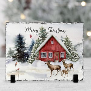 May include: A watercolor painting of a red cabin in a snowy forest with the text "Merry Christmas". Two deer and a fawn are in the foreground.