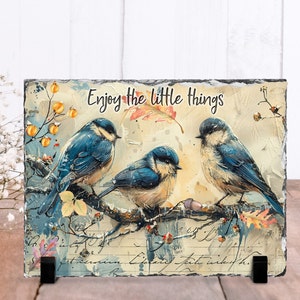 May include: A slate plaque with a vintage-inspired design featuring three blue birds perched on a branch with yellow berries and autumn leaves. The text "Enjoy the little things" is printed in black on the plaque.